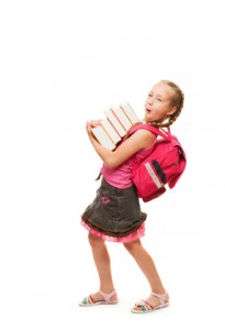 Happy little schoolgirl with a stack of heavy books....